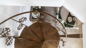 A spiral staircase with a wooden finish and decorative metal railings.