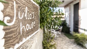 A wooden sign with "Julia's House" written on it, a stone pathway, and some greenery.