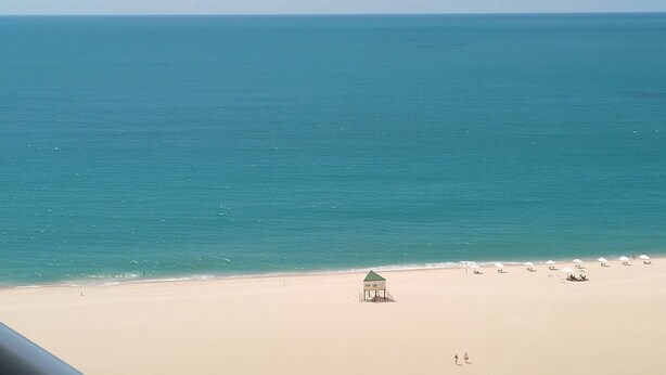 A beach with a lifeguard tower, umbrellas, and a few people. - Terraços DO Atlântico, Frente Mar, Mobiliado, Beira-mar, 19,andar (Praia de Iracema Fortaleza)