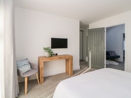 A modern bedroom with a bed, a desk, and a television on the wall.