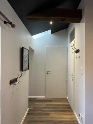 Stylish hallway with a framed picture, coat rack, and natural light pouring in through the skylight.