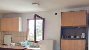 Une cuisine de taille réduite, avec des meubles de rangement en bois, un réfrigérateur blanc et une fenêtre.