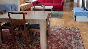 Un salon comprenant une table à manger, un canapé rouge et des tapis à motifs.