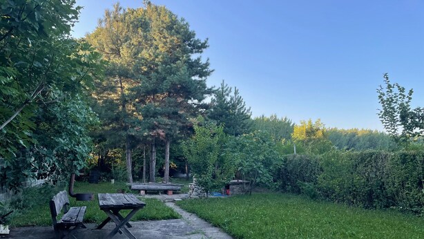 Un espace extérieur rustique avec un chemin en béton, des bancs en bois et une structure en pierre.