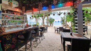 Un bar en la playa con terraza y vistas al mar.