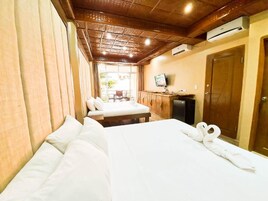 Una habitación de hotel con dos camas, techo de madera, televisor y una puerta.
