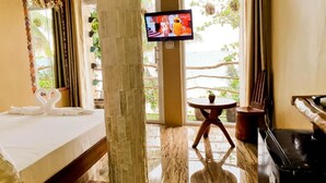 Una habitación de hotel con cama, televisión, una mesita y vista al mar.