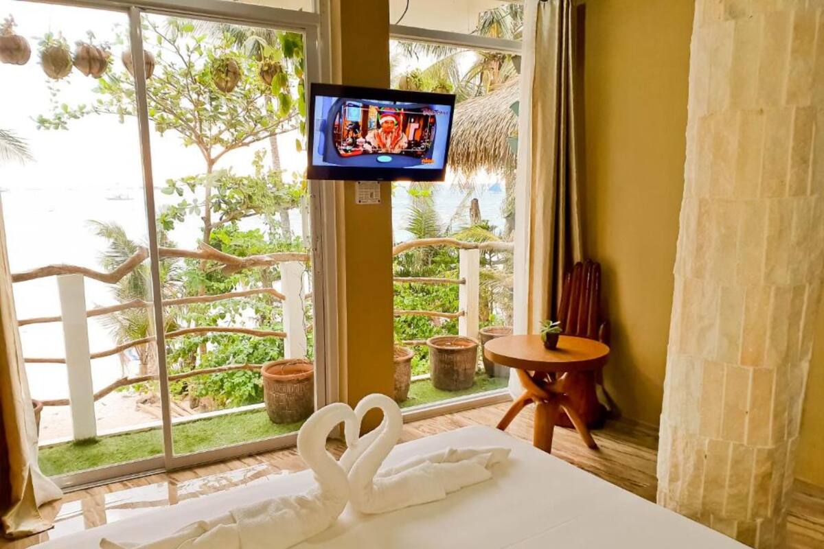 Habitación de hotel con cama, televisor, una mesita y vistas a zonas verdes.