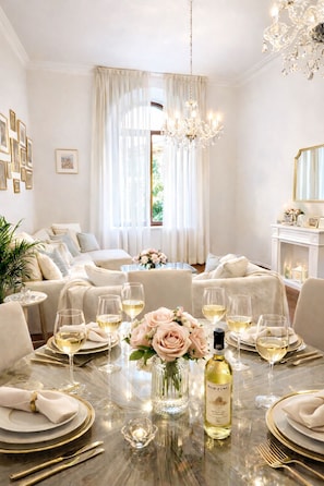 A dining area with a table set for four, featuring a bottle of wine, glasses, and a vase of flowers. - LUXURY DUOMO Magnificent 170sqm Best Central City Center Apartment (Firenze)