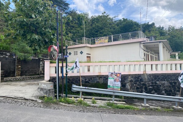 Un edificio con pared de piedra, barandilla metálica y un cartel.
