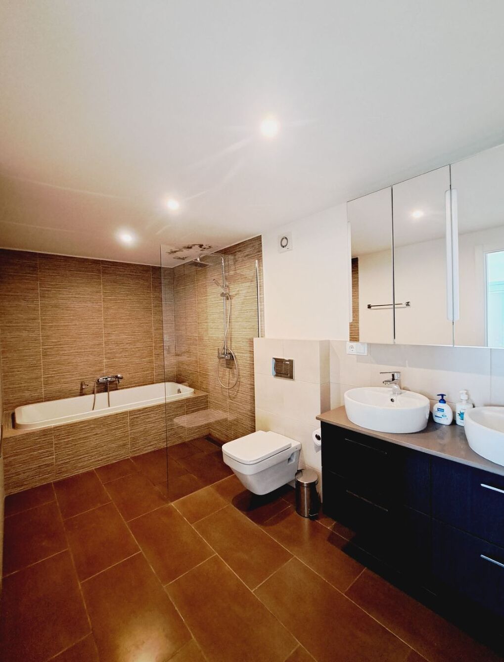 Un bagno moderno con vasca, water e mobile lavabo con lavandino e specchio.