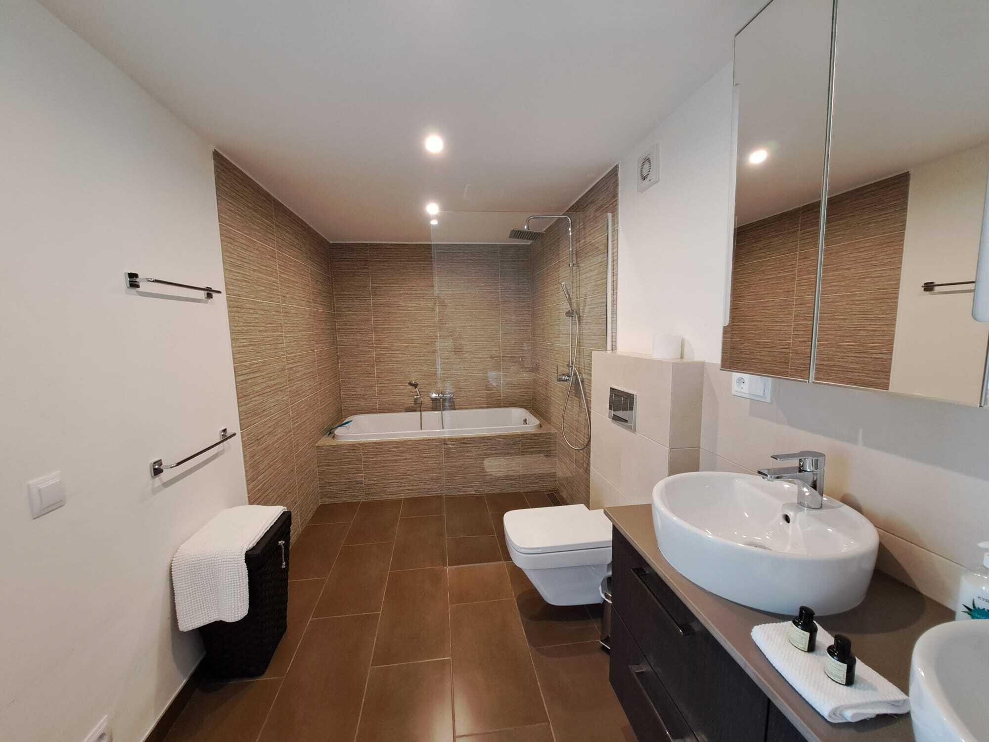 A modern bathroom with a bathtub, toilet, and sink.