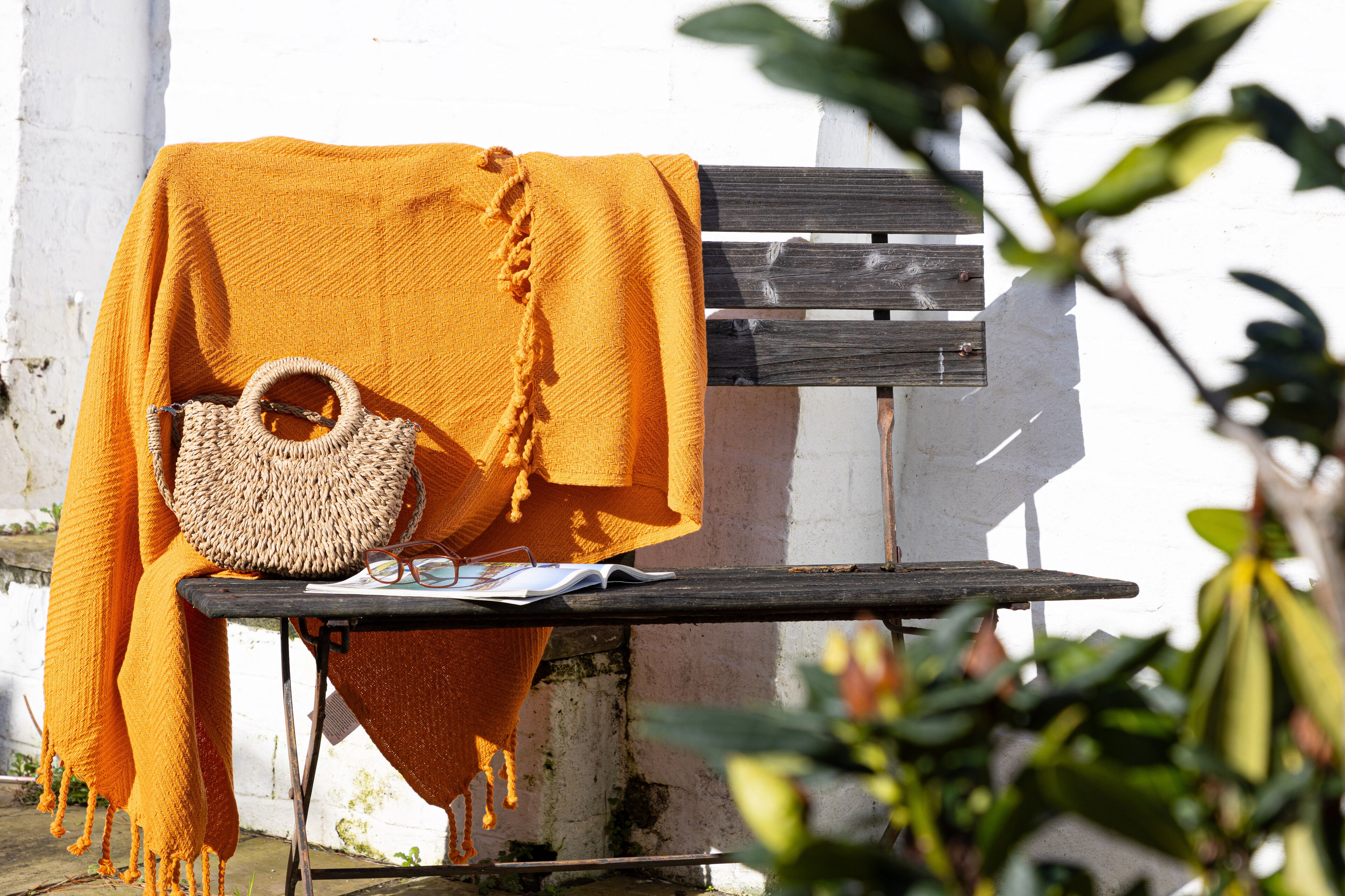 Un banc avec un sac en osier et une couverture jaune.
