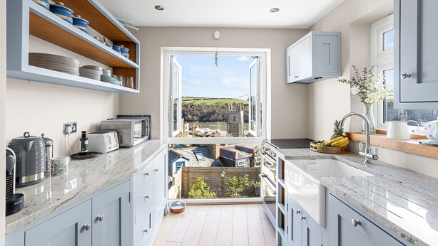 Een moderne keuken met een groot raam, inbouwplanken en uitzicht op een groen landschap.