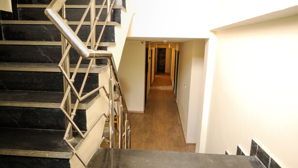 Una escalera con barandillas metálicas que lleva a un pasillo con suelo de madera.