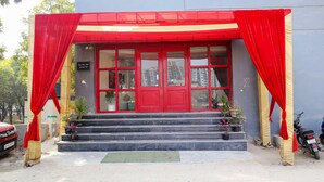 Un edificio de fachada roja, con una escalera que conduce a la entrada y macetas con plantas en los escalones.