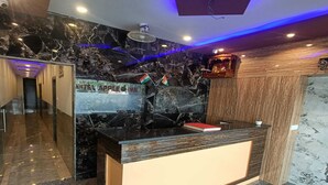A modern hotel lobby with a reception desk, marble flooring, and a ceiling with blue LED lighting. - Hotel Apple Inn (Mumbai)