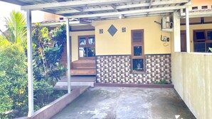 A covered outdoor area with a concrete floor, a tiled wall, and a wooden bench. - Capital O 93601 Manda Homestay Syariah (Pleret)