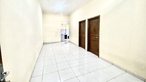 A corridor with tiled flooring, cream-colored walls, and wooden doors. - Capital O 93601 Manda Homestay Syariah (Pleret)