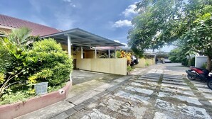 A residential area with a covered porch, a stone pathway, and a parked motorcycle. - Capital O 93601 Manda Homestay Syariah (Pleret)