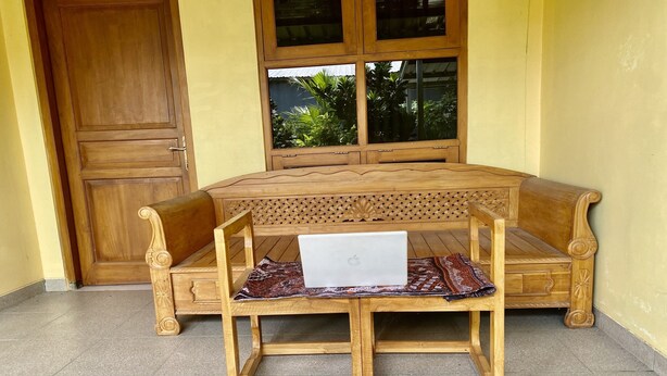 A wooden bench with a laptop and a patterned cloth. - Capital O 93601 Manda Homestay Syariah (Pleret)