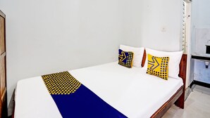 A single bed with a white mattress, a blue and yellow patterned bedspread, and two pillows with geometric designs. - Capital O 93601 Manda Homestay Syariah (Pleret)