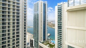 Een hoog gebouw met meerdere balkons, een jachthaven op de achtergrond, en de tekst 'LUX HOMES DUBAI'.