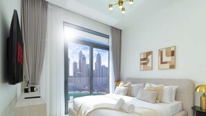 Een moderne hotelkamer met een groot bed, een flatscreen televisie, uitzicht over de stad en een minimalistische inrichting.
