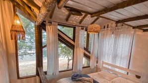 A cozy bedroom with a wooden ceiling, a bed with a white headboard, and large windows with sheer curtains. - Chalet Bromelias, Praia do Sono, Sea View (Paraty)