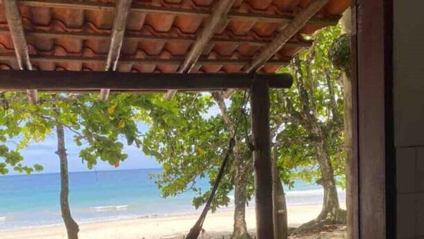 A wooden deck with a hammock and a view of a beach and ocean. - Chalet Bromelias, Praia do Sono, Sea View (Paraty)