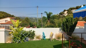 A residential garden with artificial grass, a white wall, and a view of a hilly landscape. - Villa Aucamar- Moraira (TEULADA MORAIRA)