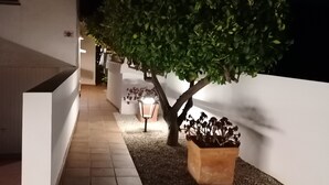 A modern outdoor area with a tree, a planter, and a pathway leading to a building. - Villa Aucamar- Moraira (TEULADA MORAIRA)