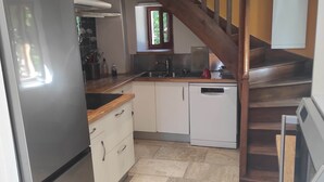 A kitchen with a stainless steel refrigerator, white cabinets, a wooden countertop, and a wooden staircase. - Lac Aigueblette Maison de Charme (Nances)