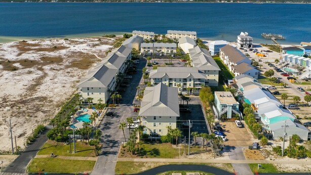 An aerial view of a coastal hotel with multiple buildings, a swimming pool, and a beach area. - Awesome condo with pool, across from beach access (Navarre)