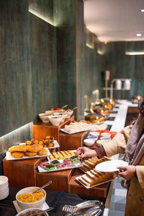 Ein reichhaltiges Buffet mit verschiedenen Speisen und einer Person, die serviert.