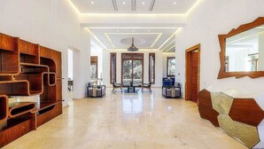 A spacious hallway with a polished marble floor, wooden shelving units, and a large mirror on the right. - Villa Hana A (Marrakech)