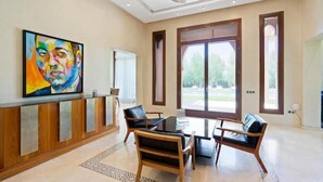 A modern hotel lobby with a reception desk, seating area, and large windows offering a view of the outdoors. - Villa Hana A (Marrakech)