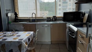 Una cocina compacta con una mesa de comedor, microondas, hervidor de agua y lavavajillas.