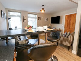 Una cocina moderna con comedor, que cuenta con una isla grande, sillas de cuero negro y un televisor de pantalla plana montado en la pared.
