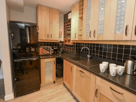 Una cocina moderna con armarios de madera, salpicadero de azulejos negros, electrodomésticos de acero inoxidable y una estación para café.
