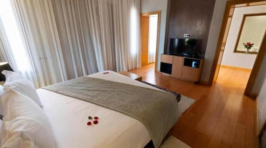 Una habitación de hotel con una cama grande, un televisor y suelo de madera.