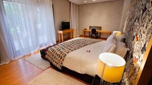 Une chambre à coucher comprenant un lit, un bureau, une chaise, une télévision et une lampe.