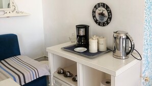 A small, neatly organized room with a bed, a bedside table with a kettle, cups, and a clock. - Magnificent S+1 with panoramic view of Port El Kantaoui (Hammam Sousse)