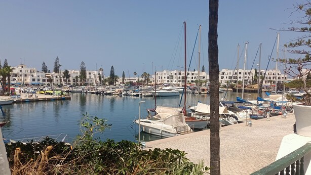 A marina with boats docked, a clear sky, and buildings in the background. - Magnificent S+1 with panoramic view of Port El Kantaoui (Hammam Sousse)