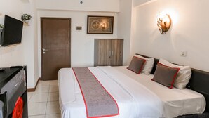 A hotel room with a bed, a television, a wardrobe, and a wall-mounted light fixture. - Capital O 93593 Pelangi Loftville City (South Tangerang)