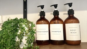 Trois flacons de produits de soins pour le corps sont posés sur une étagère.