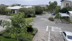 Un parking avec des places délimitées, un panneau de signalisation indiquant un arrêt obligatoire, et un bâtiment avec un toit plat en arrière-plan.