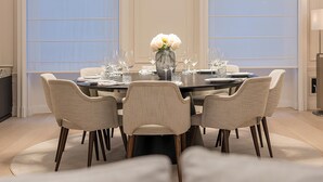 A dining room with a round table, six chairs, and a vase of flowers.
