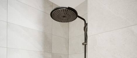A shower with a handheld showerhead and a wall-mounted control panel.