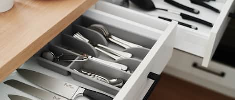 A kitchen drawer with neatly organized utensils and cutlery, including knives, spoons, and forks.